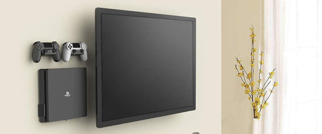 PlayStation console and two controllers wall-mounted next to a flat screen TV for a tidy gaming setup