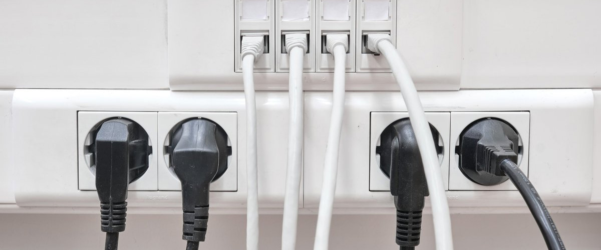 Close-up of organized TV wires and power cables plugged neatly into outlets, demonstrating professional cable management