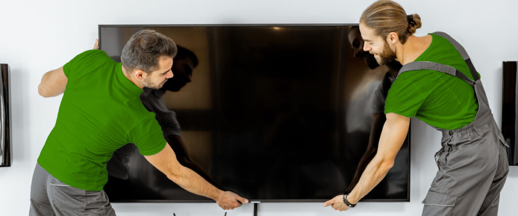Two professional installers securing a flat screen TV to the wall as part of same-day mounting service