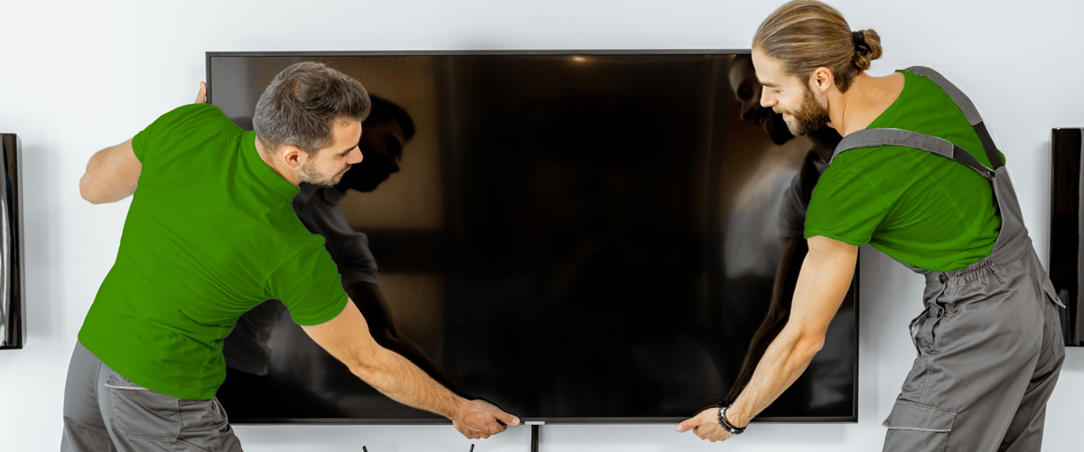 Two professional installers securing a flat screen TV to the wall as part of same-day mounting service