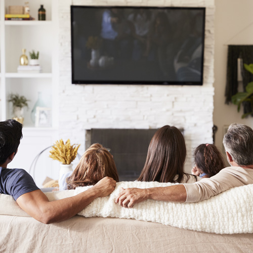 Family watching TV mounted above fireplace