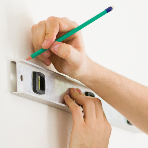 Marking a wall with a level and pencil